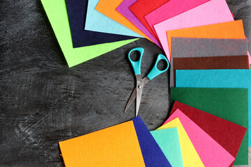  Felt fabric of different colors and scissors on dark background with copy space. Crafts and hobby...