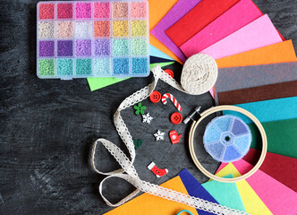 Colorful picture of craft supplies. Felt fabric, glass beads, embroidery hoop, scissors and tread on dark background. Hobby and free time concept. 