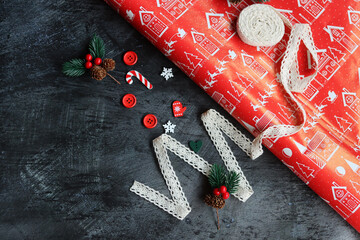 Christmas background with red wrapping paper, snowflakes, candy canes, lace ribbon and fir branches on dark background