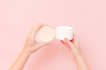 Round jar of cosmetic cream in hand on pink background. Cosmetics beauty mockup for product branding