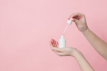 Hands hold glass unbranded bottle with serum or essential oil with pipette. Concept of beauty. Product cosmetic advertising