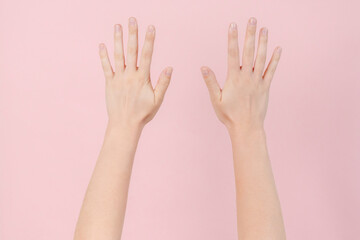 Manicured nails, beautiful woman hands forming an elegant shape on pink background