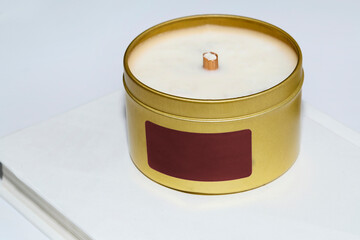 Luxury candle in a colorful tin with a blank label. Photograph with a white background and space for copy. Gold and red design.