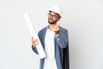 Young architect man with helmet and holding blueprints isolated on white background making money gesture