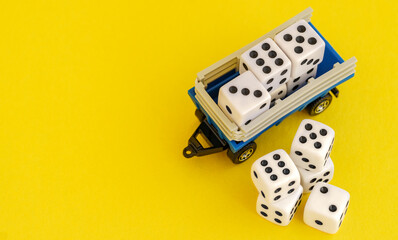 A toy truck loaded with dice on a yellow background, symbolizing the unpredictable nature of...