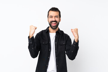 Young man with beard over isolated white background celebrating a victory in winner position