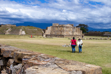 Two women walking through the archaeological site of Monte Alban in Oaxaca Mexico.