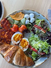 delicious breakfast with eggs, sausages, salad, croissants, tomatoes and cheese