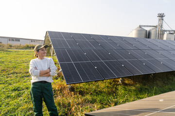 Female farmer on a modern farm using solar panels. Agricultural silos in the background.