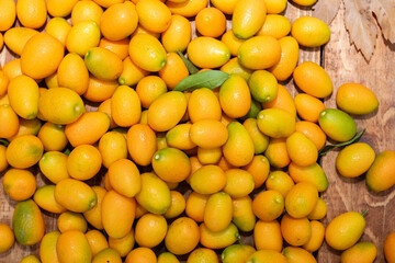 A pile of kumquat fruit on a wooden floor.
