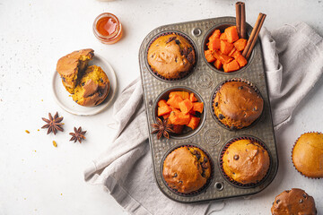 Homemade spicy pumpkin muffins or cupcakes with chocolate on a metal rack, top view. Autumn dessert. Selective focus