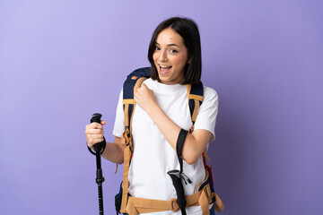 Young caucasian woman with backpack and trekking poles isolated on blue background celebrating a victory