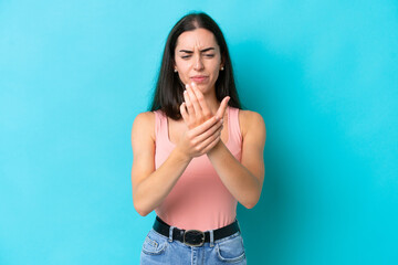 Young caucasian woman isolated on blue background suffering from pain in hands