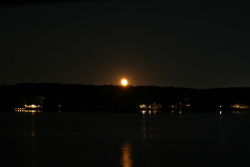 Obraz premium Moonrise Above Shoreline Town Lights Along the Niantic River at Night in Niantic, Connecticut