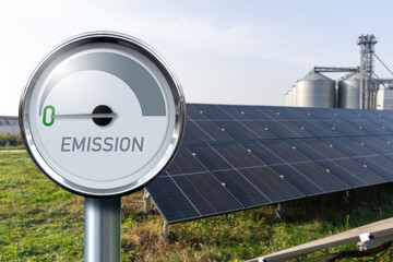 Gauge with inscription EMISSION on a background of renewable energy sources. Arrow points to zero....