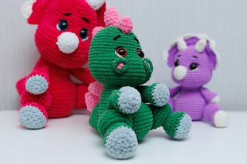 Knitted handmade dinosaur toys on a white background.