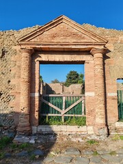 Ostia Antica, Rome, Italy - November 3, 2024. Remains of the entrance with evidence of the entablature of a brick building dating back to the Roman Empire, in the Archaeological Park of Ostia Antica.