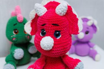 Knitted handmade dinosaur toys on a white background.