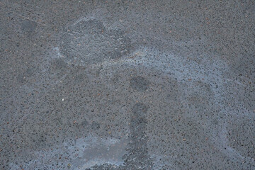 Colored texture of oil products on asphalt in bright sunlight after rain.