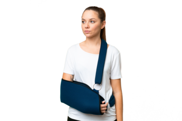Young blonde woman with broken arm and wearing a sling over isolated chroma key background looking to the side