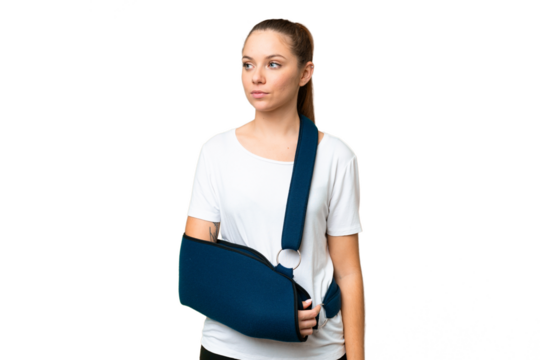 Young blonde woman with broken arm and wearing a sling over isolated chroma key background looking to the side