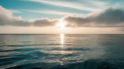 Fototapeta premium Serene Horizon: The tranquil expanse of the ocean meets the sky in a breathtaking display of natural beauty, with the sun breaking through the clouds, casting a warm glow on the water.