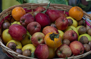 A bountiful basket filled with an assortment of ripe fruits including apples, persimmons, and pears, showcasing a harvest of vibrant, fresh produce