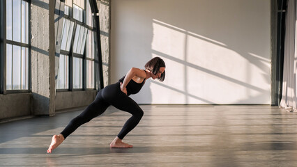 Pilates training. Balance exercise. Athletic woman in activewear practice sport yoga pose gymnastic workout muscle stretch in gym fitness studio loft interior.