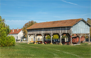 Old barn building with all sorts of farmimg equipment stored under it