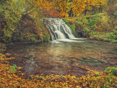 view to waterfall with little lagoon in autumn canyon