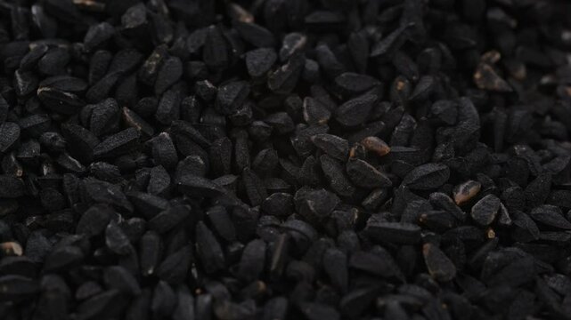 Top view, macro. Heap of dry black cumin seeds, slider shot. Shallow depth of field, selective focus. Ingredients, food seasoning, cooking, spices, flavor concepts. 4k