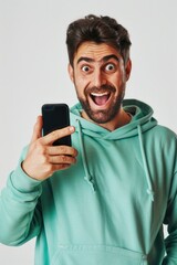 A person wearing a green hoodie holds a cell phone, possibly taking a call or checking messages