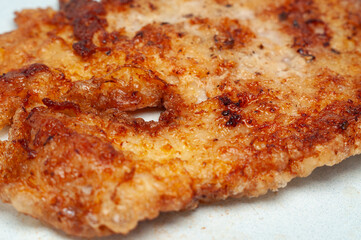 A golden-brown, crispy fried chicken breast sits on a white plate