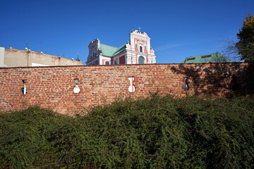 facade of a baroque church behind a medieval defensive wall in the city of Poznan