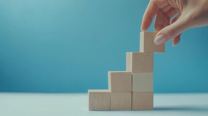 Business concept growth success process, close-up of a woman hand arranging wood blocks stacking as step stairs on a paper blue background