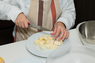 Close-up of female hand preparing cubed butter in kitchen. Stage of cooking pie