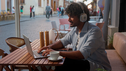 Indian Arabian man male businessman client business guy online work in cafe distant education using devices laptop phone listen music in headphones outdoors tourist traveler customer drink coffee city