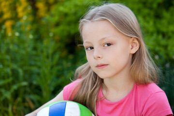 Close up portrait of a six year little girl, against background of summer park