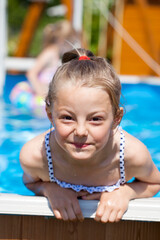 Child girl in blue bikini near swimming pool. Hot Summer