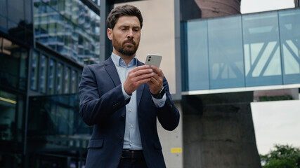 Caucasian man browsing mobile phone data connections city downtown male business employer adult businessman investor guy owner focused scrolling smartphone screen online app gadget addicted outdoors
