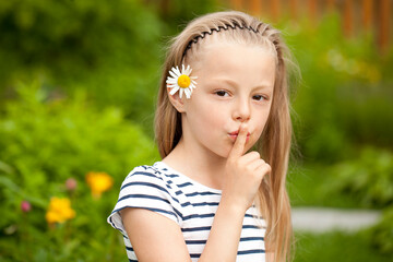 Little girl has put forefinger to lips as sign of silence