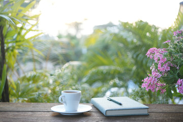 A White tea cup with Verbena flower and notebook, outdoor working
