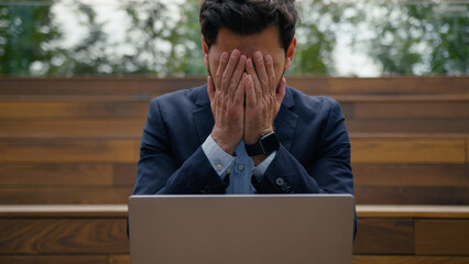 Caucasian businessman guy male entrepreneur remote work using pc laptop outdoors frustrated sad anxious stressed business man computer error crash breakdown tech problem failure scam bad news in city