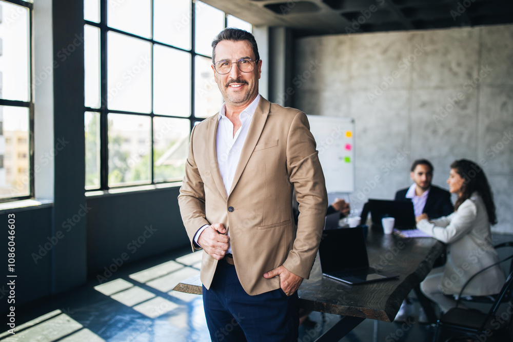 Aufkleber a well-dressed man smiles while standing in a contemporary office with large windows. colleagues are