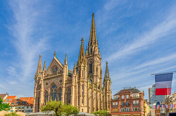 Temple Saint-Etienne Calvinist church Cathedral of Mulhouse building and France flag on Place de la Reunion square in old town Mulhouse city historic centre, Alsace Grand Est region, France