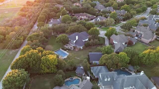 Mansion houses with large backyard swimming pool in upscale residential neighborhood near suburban park long walking biking path in Midway Road, Plano, Texas, lush greenery trees sunset, flyover