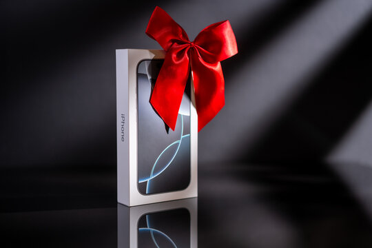 a box of new  Apple iPhone 16 pro  with red bow like a gift on black background. The latest model of Apple mobile phones. Copy space.