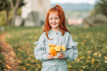 Ginger, redhead girl holding a basket with orange and yellow flowers