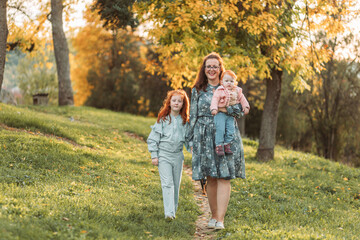 Fototapeta premium Young mom with her little ginger daughters. Mothers day, connection