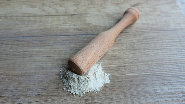 Zeolite in a wooden mortar with a pestle. Zeolite mesolite raw powder on wooden background